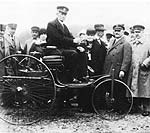 Karl Benz auf dem Patent-Motorwagen im Jahre 1925, whrend der Verkehrsaustellung in Mnchen auf der Theresienwiese.